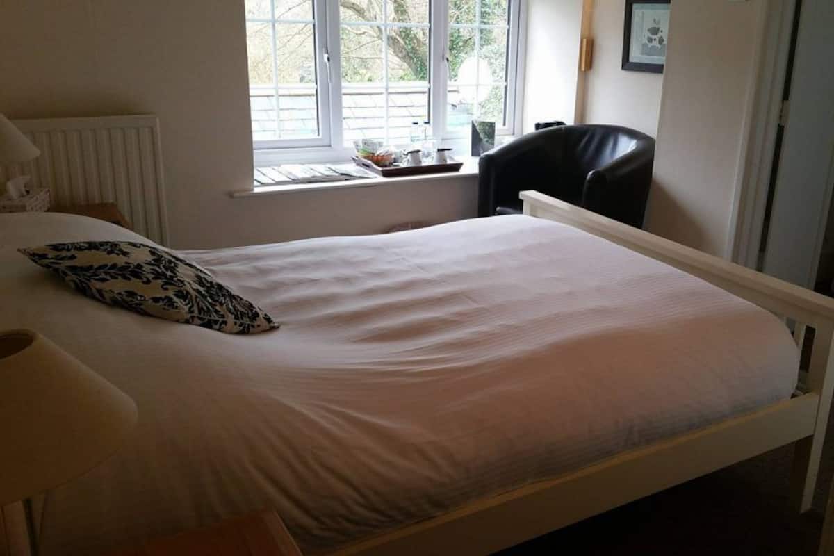 A bedroom with a bed, a chair, a window, and a radiator.