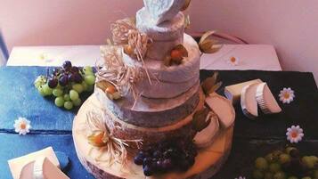 A multi-tiered cake with fruits and flowers on a wooden board.