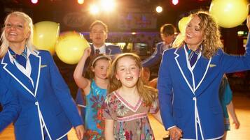 A group of people in blue uniforms holding yellow balloons in a brightly lit indoor setting.