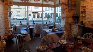 A restaurant with brick walls, hanging light fixtures, and a view of the street outside. - Driftwood Hotel (Blackpool)