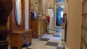 A hallway with a checkered floor, wooden furniture, a large mirror, and a staircase in the background. - Driftwood Hotel (Blackpool)
