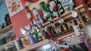 A bar with various liquor bottles and a sign that reads "WINE". - Driftwood Hotel (Blackpool)