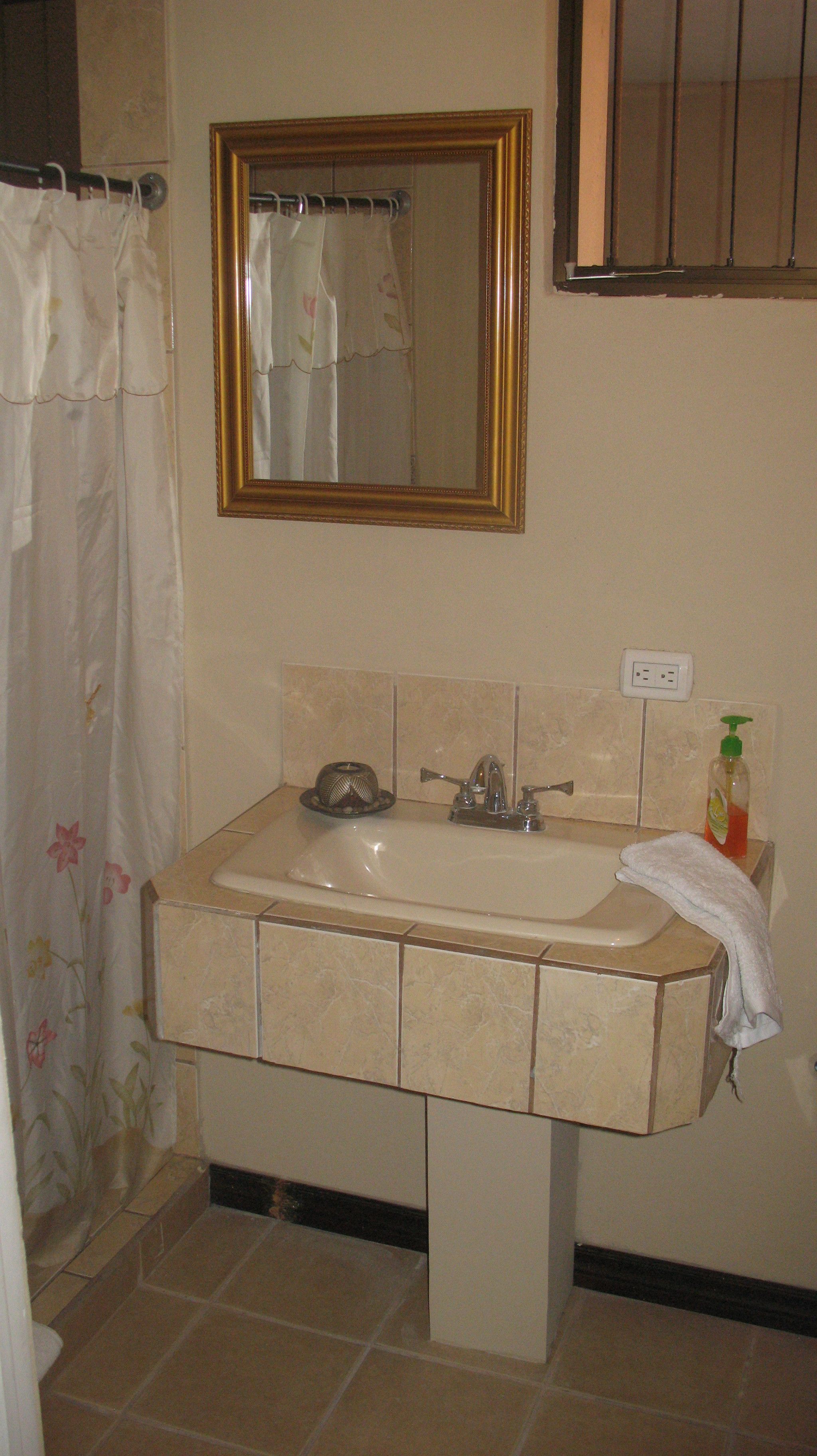 A bathroom with a sink, mirror, and shower curtain.