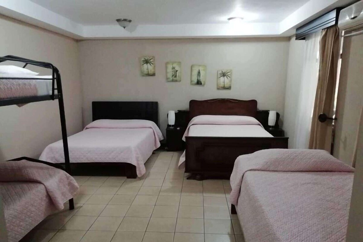 Une chambre avec des lits superposés, une table de chevet, une lampe et un mur orné de tableaux.
