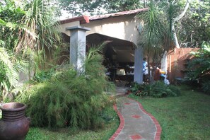 A covered outdoor area with a brick pathway leading to a building.