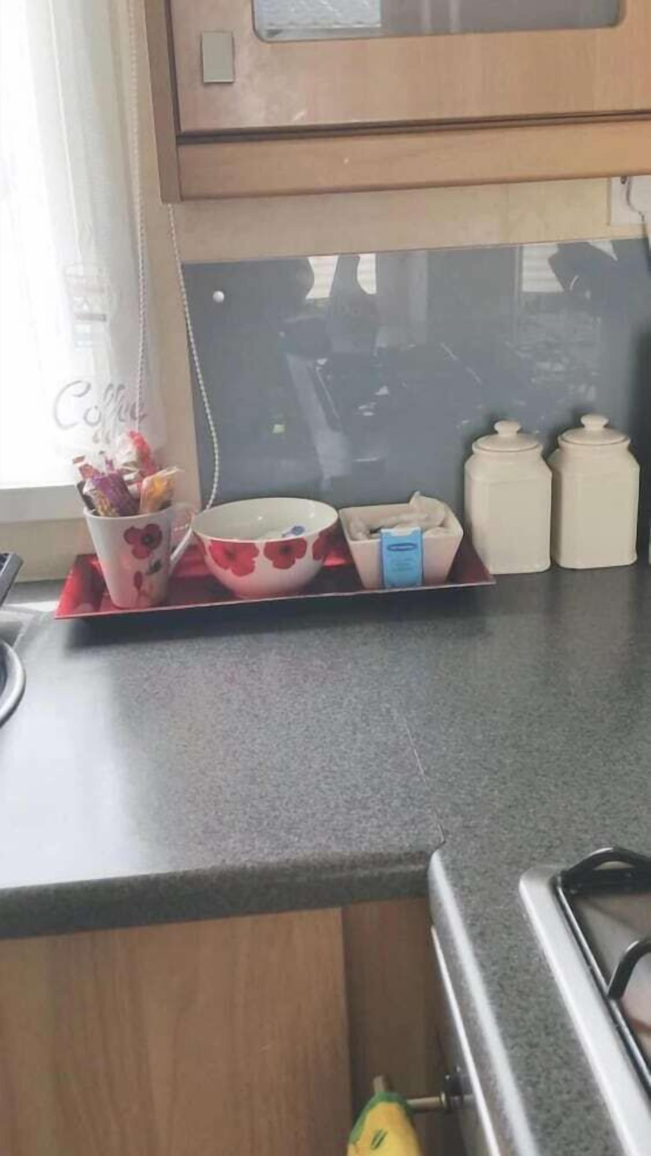A kitchen counter with a coffee maker, a bowl, a tray, and two containers.