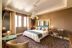 Una camera d'albergo con un letto grande, una scrivania, una sedia e un televisore.