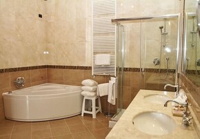 A modern bathroom with a large bathtub, a glass-enclosed shower, and a vanity with two sinks.