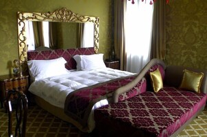 A hotel room with a large bed, a nightstand, a dresser, and a chair.