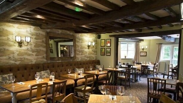 Ein Restaurant mit Holztischen und -stühlen, Steinwänden und einer gemütlichen Atmosphäre.