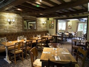 Un restaurante con mesas y sillas de madera, paredes de piedra y un ambiente acogedor.