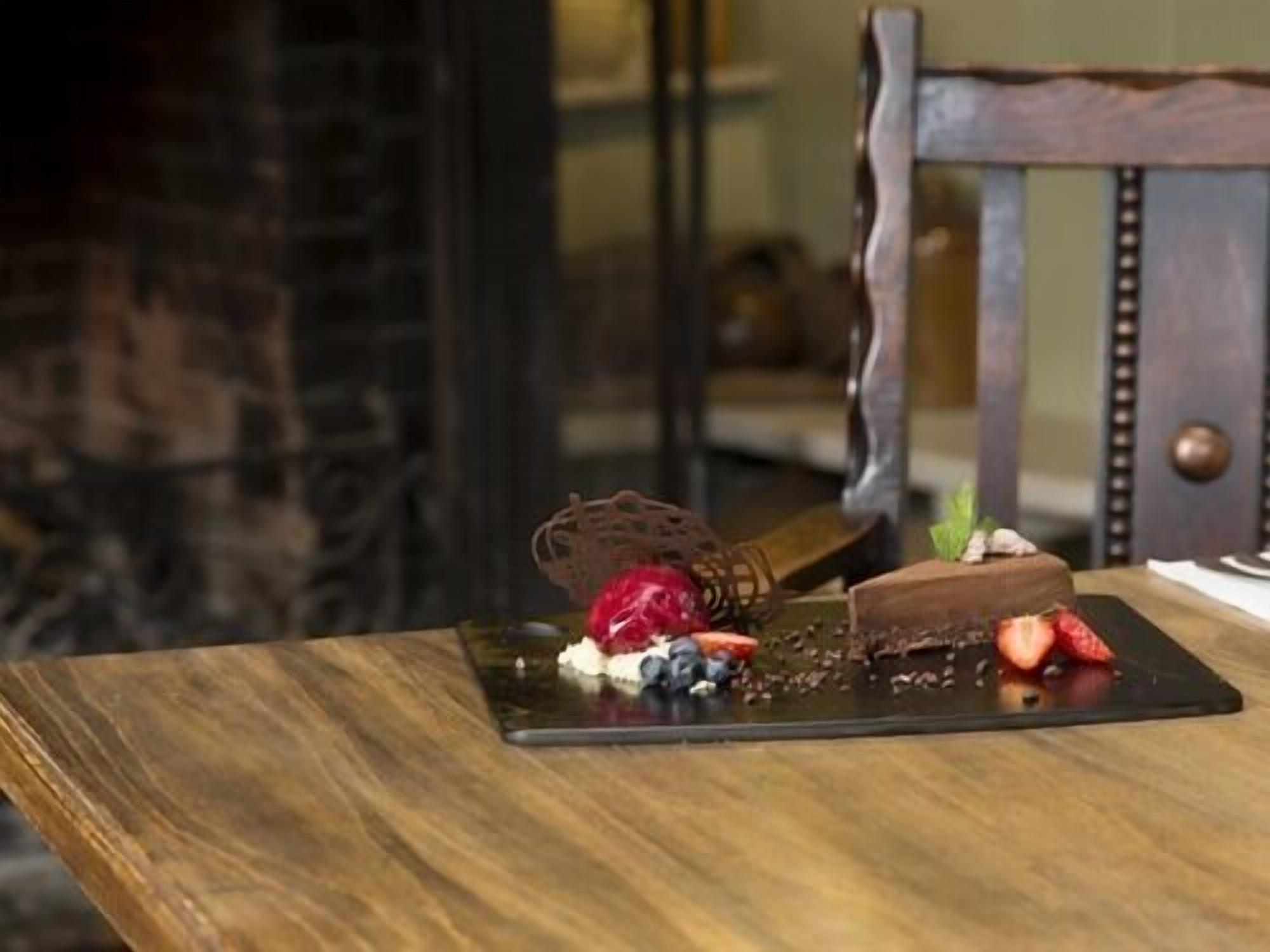 Un plato de postre con chocolate y fresas sobre una mesa de madera.