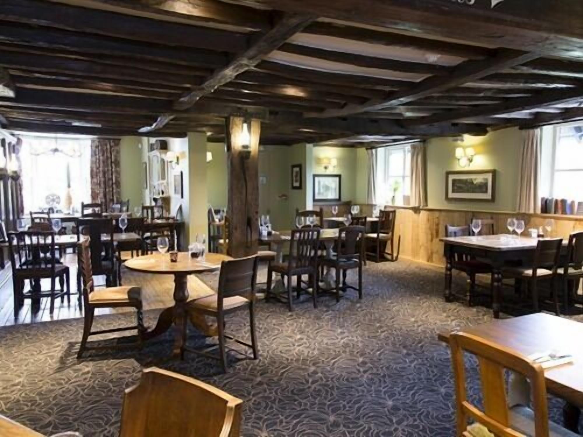 Ein Restaurant mit Holzbalkendecke, runden Tischen und Stühlen.