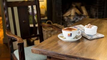 Uma mesa de madeira com uma xícara de café e uma tigela pequena de marshmallows.