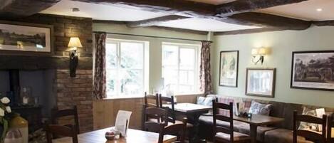 A cozy room with a fireplace, wooden furniture, and framed pictures on the walls.