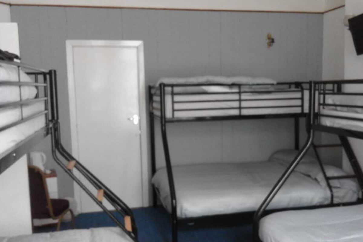 A bunk bed room with a door and a television on the wall.