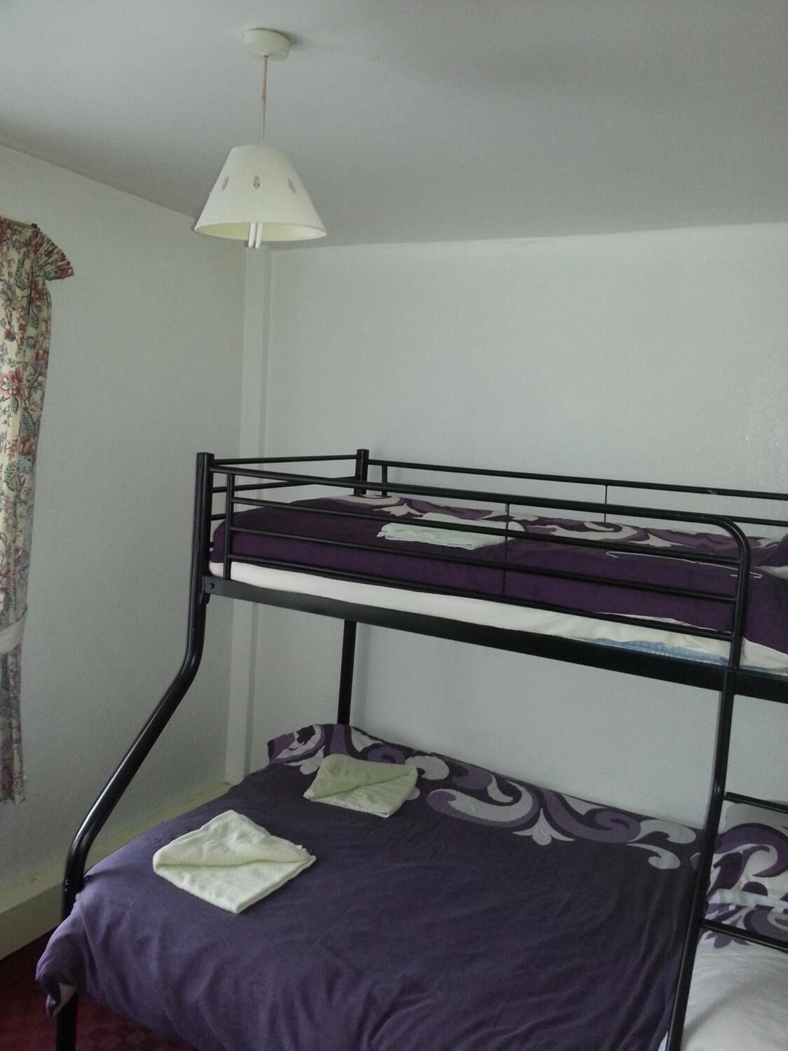 A bunk bed with a purple bedspread and a white pillow on the lower bunk.