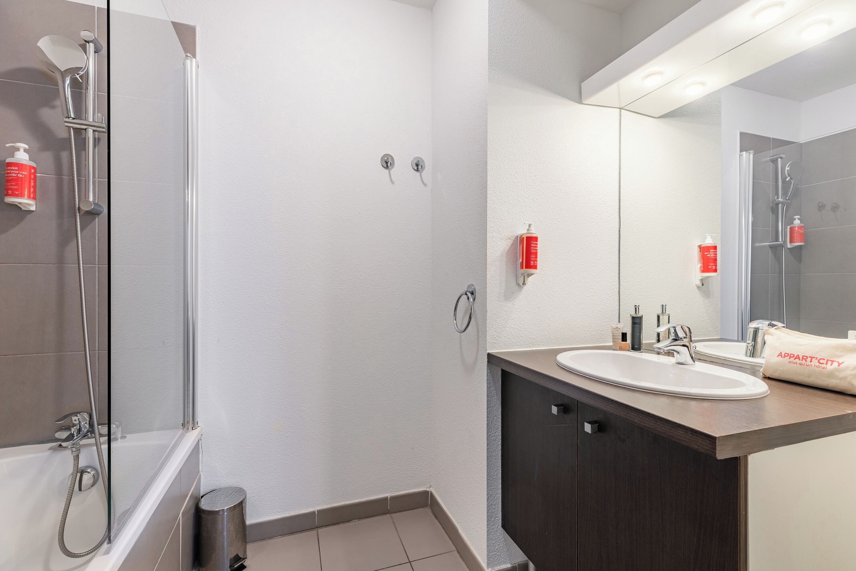 Un baño moderno con cabina de ducha de vidrio, lavabo con espejo y artículos de aseo en la encimera.