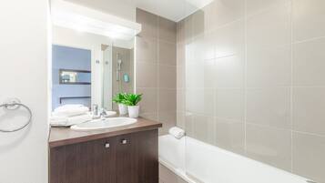 Une salle de bain moderne avec un meuble-lavabo en bois, un lavabo blanc, un miroir et une baignoire.