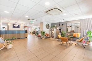 Un hall espacioso con mostrador de recepción, zona de estar y pared con diseño.