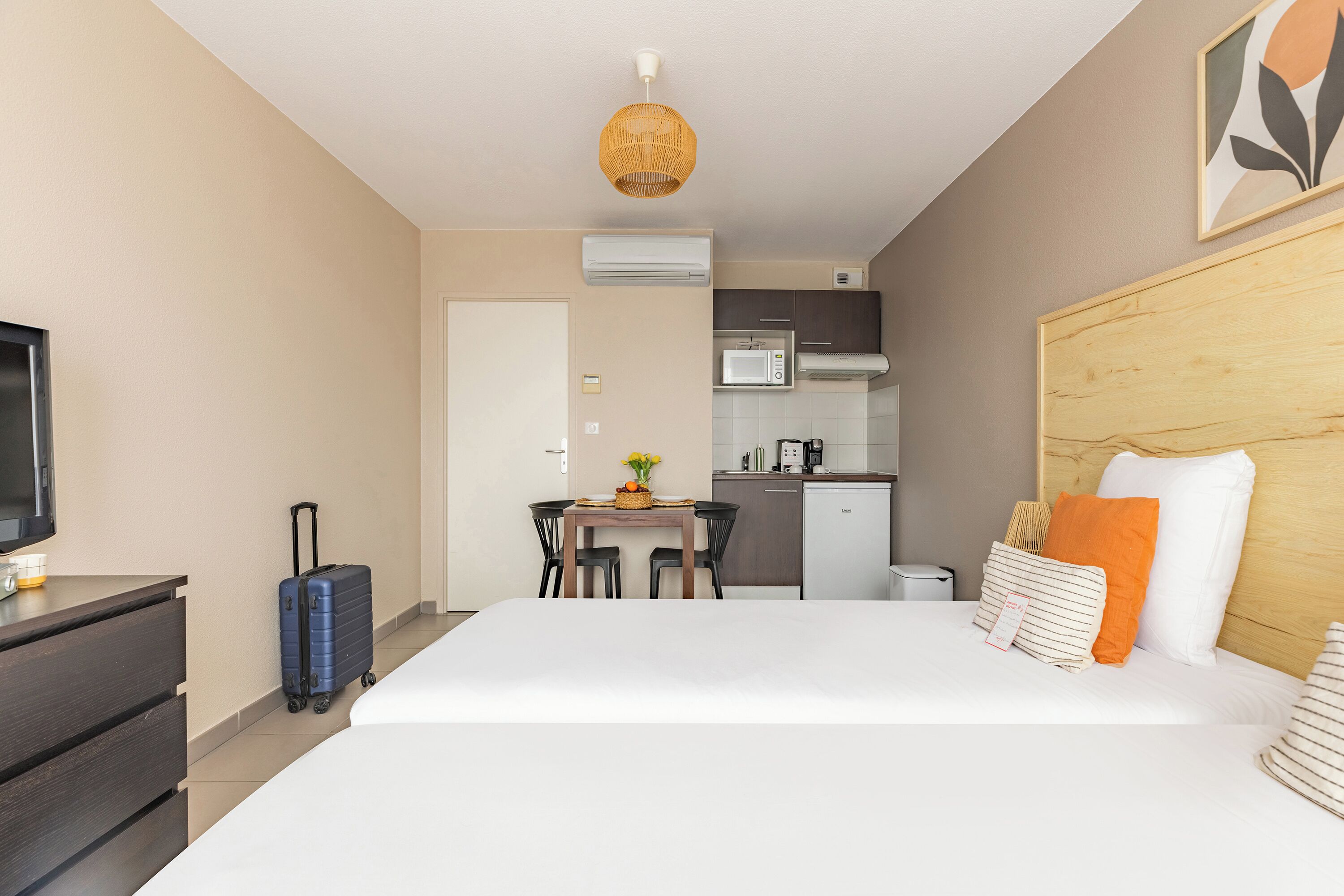 Ein Hotelzimmer mit Bett, Schreibtisch, einer Küchenzeile und einem Fernseher.