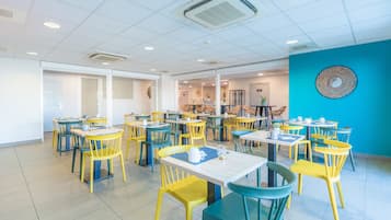 A dining area with multiple tables and chairs, a blue accent wall, and a ceiling with recessed lighting.