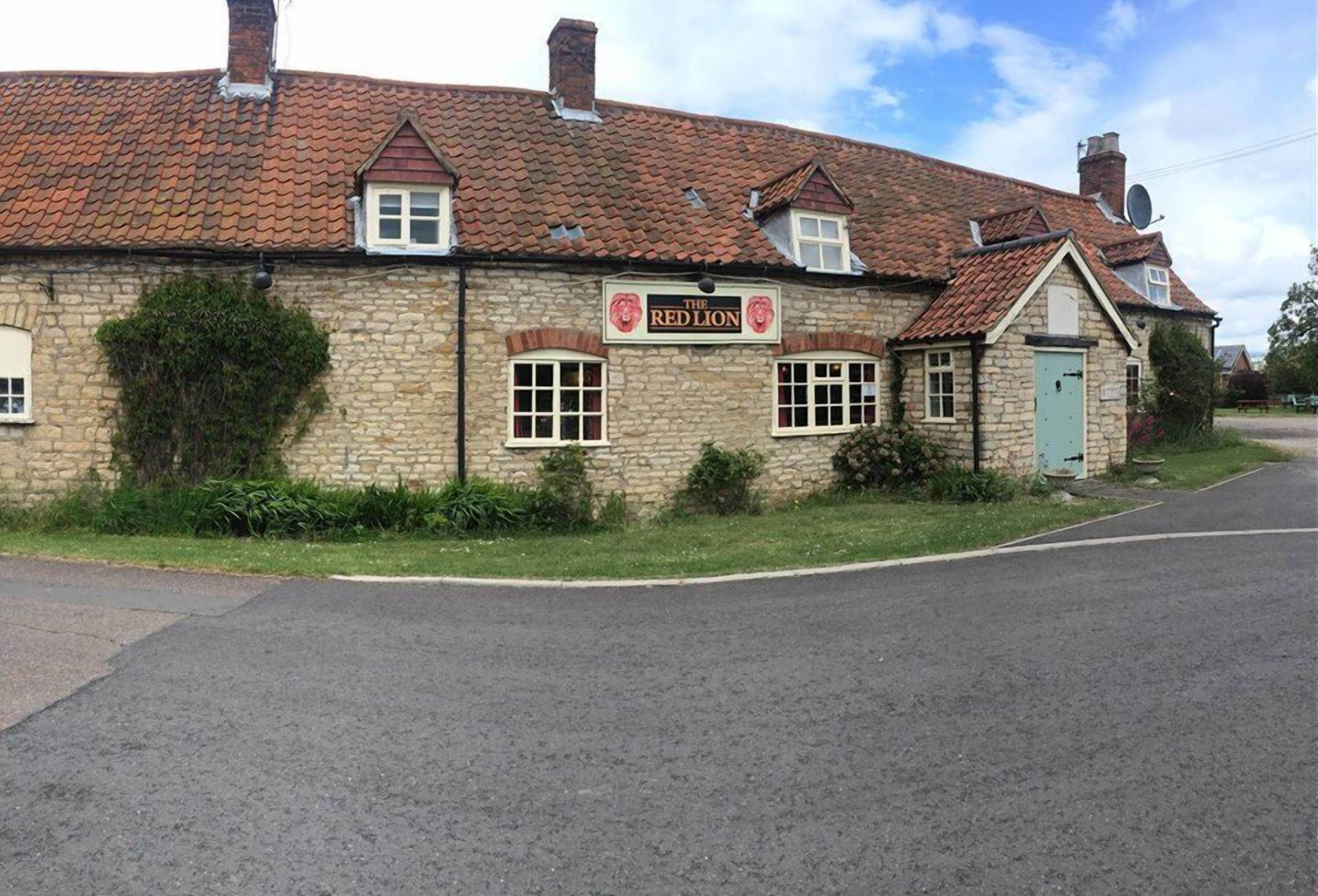 En bygning af sten med et skilt, der viser "The Red Lion".