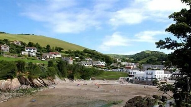A coastal town with houses on a hillside, a beach, and rocky terrain. - Saffron House Hotel (Ilfracombe)