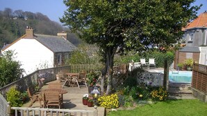A backyard with a wooden deck, outdoor furniture, a tree, and a swimming pool. - Saffron House Hotel (Ilfracombe)