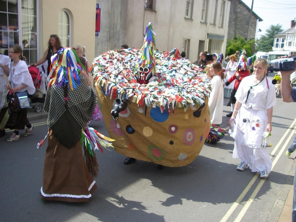 Un desfile callejero con un carroza grande y decorada con un pastel.