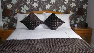 A bed with a white sheet, two dark patterned pillows, and a dark textured blanket.