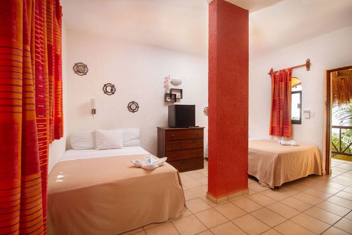 Habitació d'hotel amb dos llits, televisió, un taulell i una finestra amb cortines.
