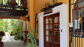 Une entrée d’immeuble avec une enseigne indiquant « Centre de plongée », des plantes en pot et une porte grillagée.