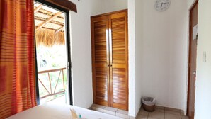 Une chambre à coucher avec un lit, une porte en bois, une horloge et une fenêtre avec des rideaux.