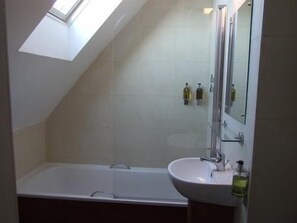 A bathroom with a skylight, a bathtub, a sink, and two bottles of soap. - Leith House (Edinburgh)