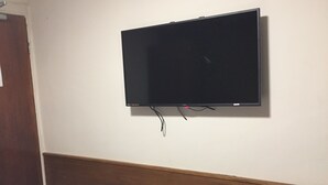 Televisor de pantalla plana montado en una pared blanca con un panel de madera debajo.