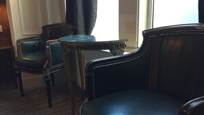 Una habitación con un sofá de cuero oscuro, un sillón a juego y una mesita con patas ornamentadas.