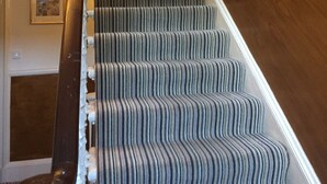 Una escalera con alfombra a rayas y barandillas de madera.