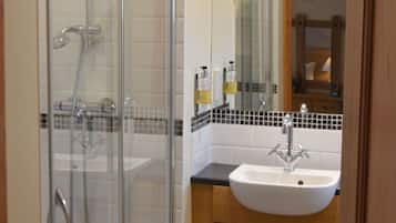 A bathroom with a glass shower enclosure, a sink, and wooden cabinets.