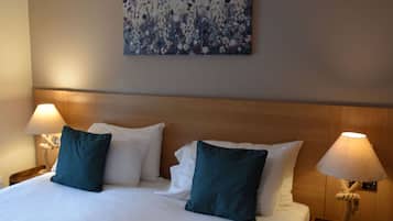 Habitació d'hotel amb un llit gran, dues làmpades de nit i una obra d'art floral a la paret.