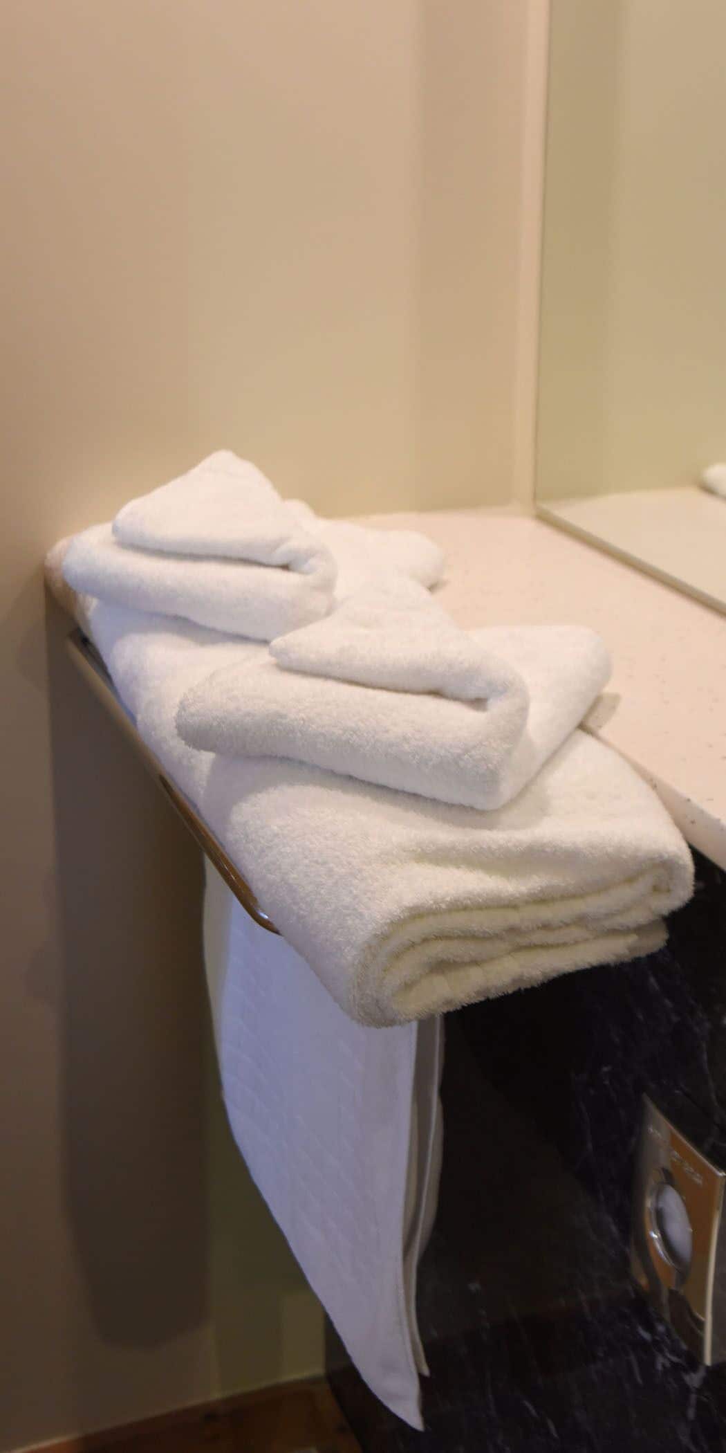 Un montón de toallas blancas sobre un toallero adherido a la pared en un baño.