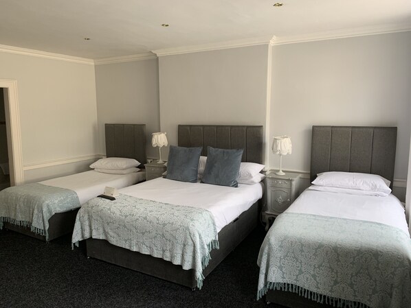 Cozy retreat with a central bed and two smaller beds, each with a bedside table for convenience.