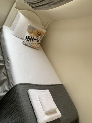 Restful retreat with a neatly made bed, featuring a quilted blanket and a decorative pillow.