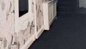 A hallway with a marble wall, a white door, and a staircase leading to another room. - Bide Collective (Edinburgh)