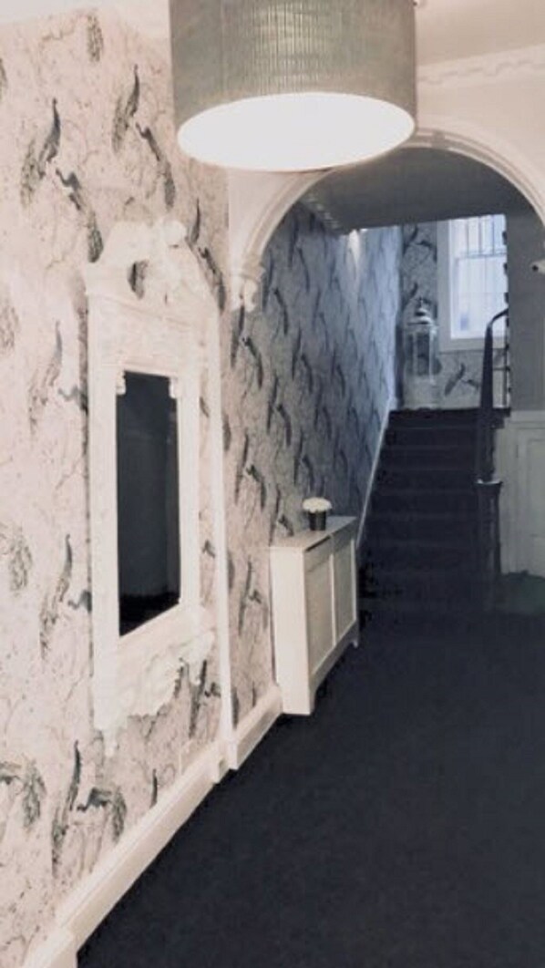 Un pasillo con pared de mármol, una puerta blanca y una escalera que lleva a otra habitación.