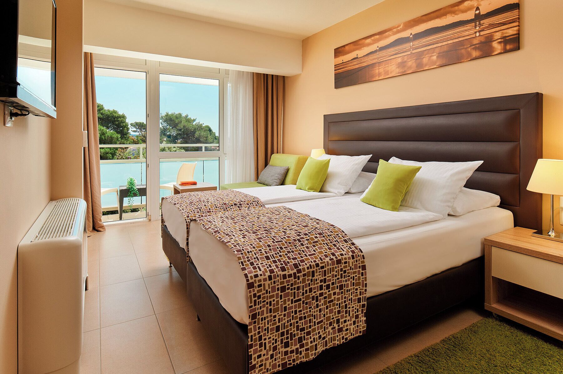 A hotel room with a large bed, a bedside table, a TV, and a view of the outdoors.