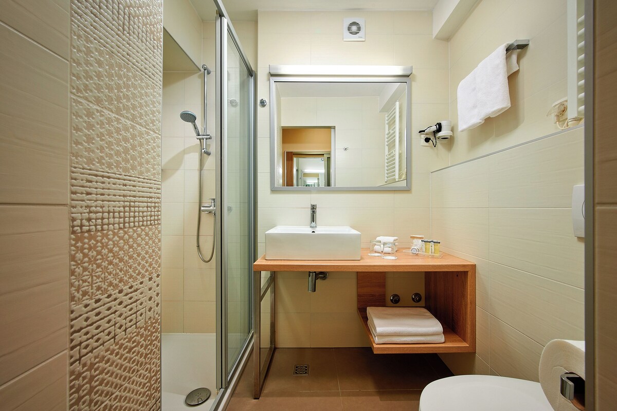 Un baño moderno con cabina de ducha de vidrio, un lavabo blanco y un espejo encima.