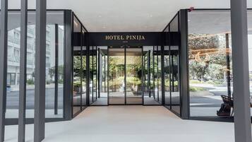 Hotel Pinija's entrance features a glass facade offering views of the surrounding greenery.