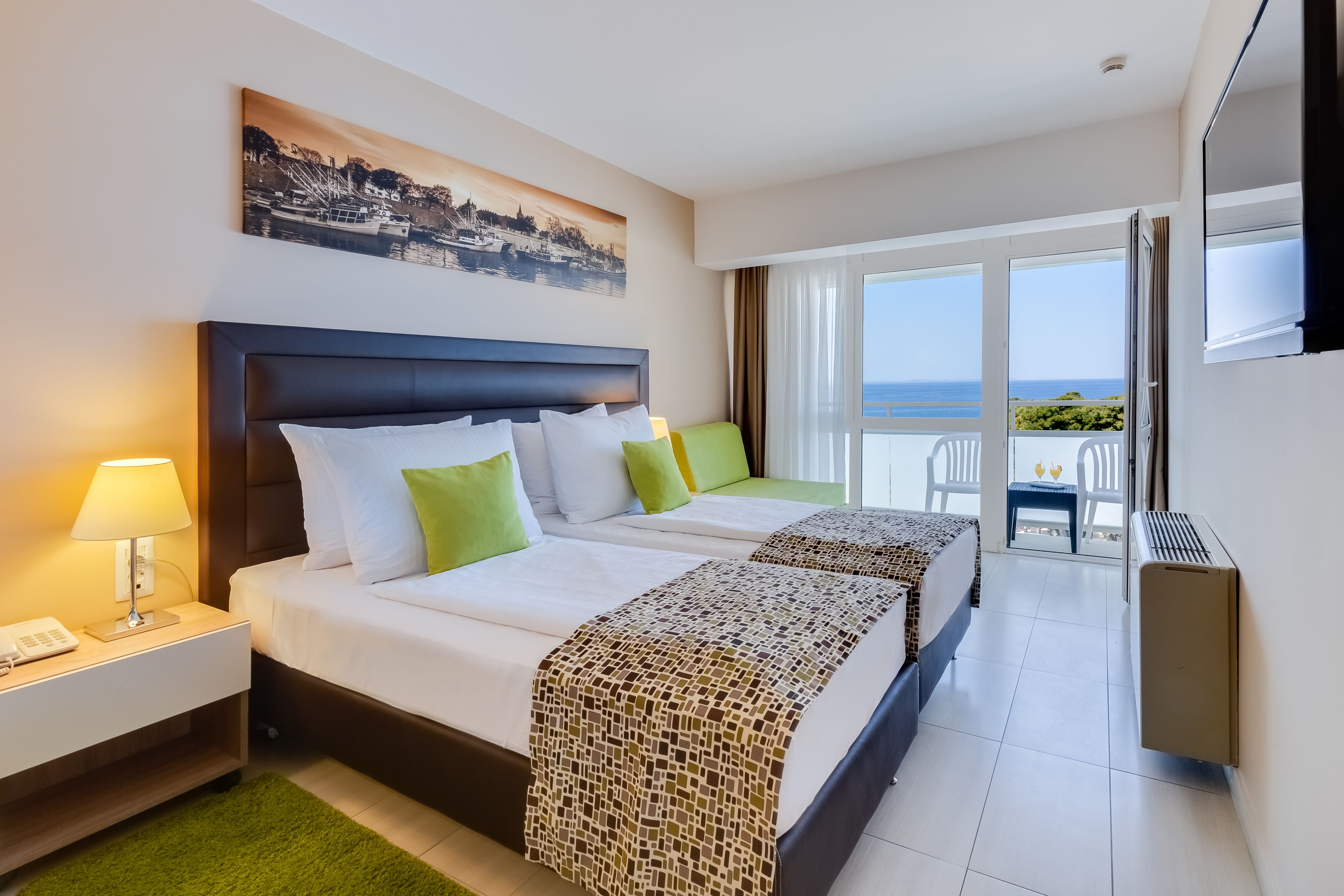 Quarto de hotel com duas camas, varanda e vista, televisão de tela plana e telefone na mesa de cabeceira.