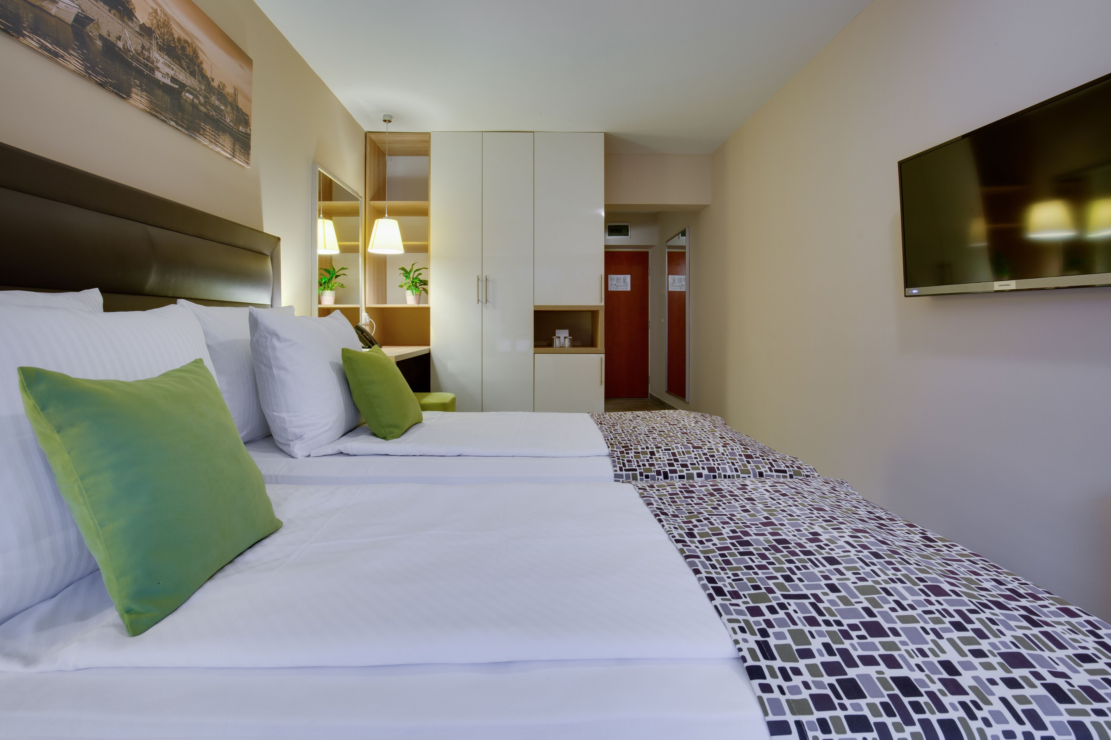 Une chambre d’hôtel avec un grand lit, une télévision, une armoire et un petit bureau.